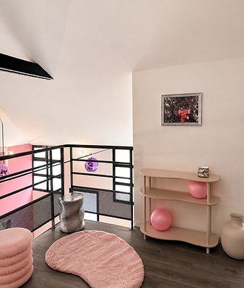 Mezzanine détente du studio avec tapis rose, console et boule à facettes